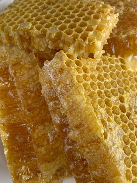 A pile of honeycomb with honey shining on its surfaces.