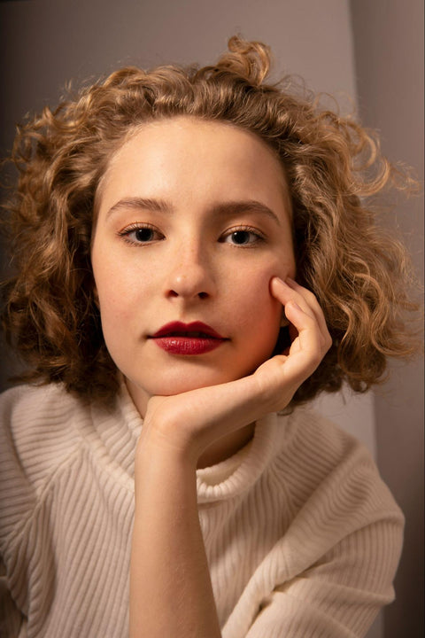 A woman with glowing skin wearing red lipstick.