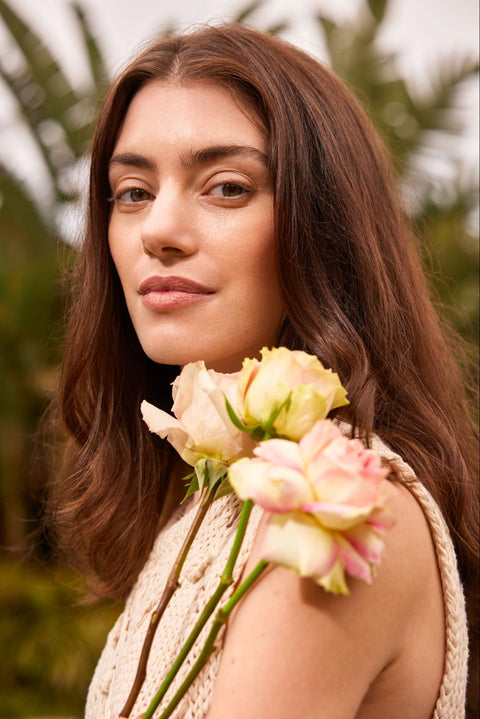 A woman with clear and bright skin holding flowers.