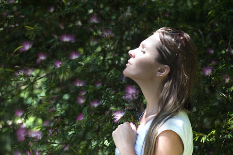 A woman pausing in a garden, with sun on her face