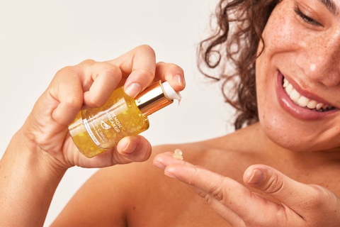 A woman pumping out vitamin c serum on her fingertips